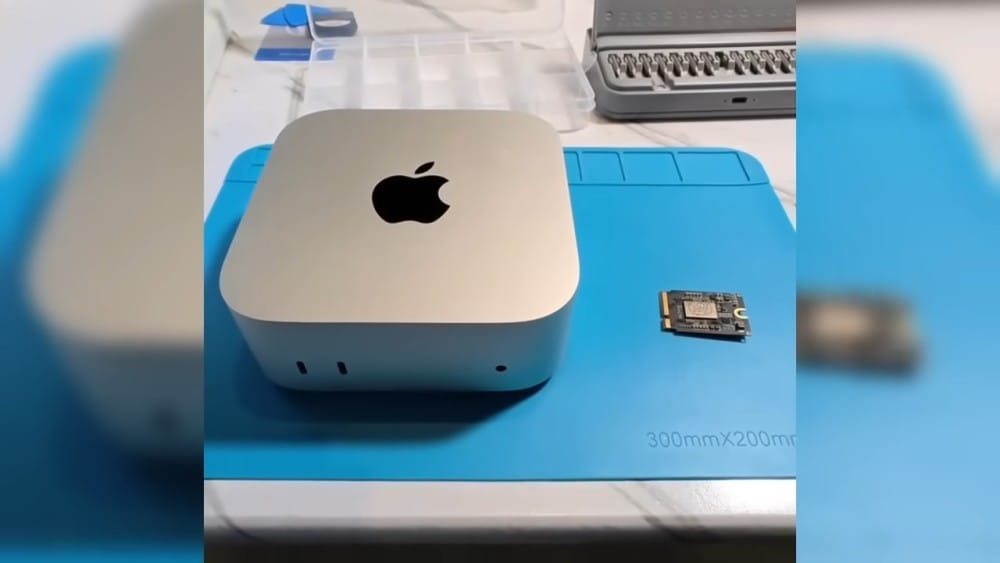 Крупный план Apple Mac mini рядом с небольшой платой на синем коврике для ремонта.