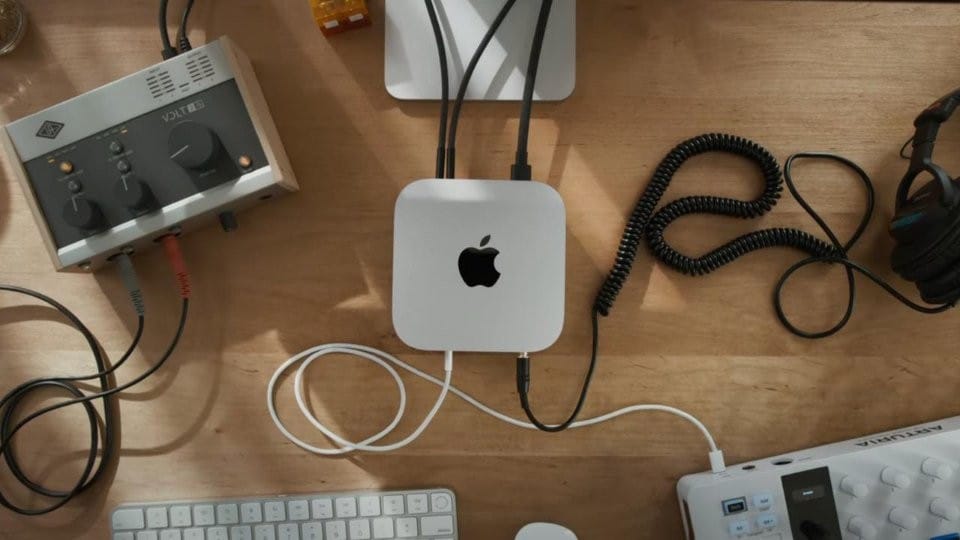 Настольная конфигурация с Apple M4 Mac Mini, аудиоинтерфейсом, клавиатурой и наушниками, демонстрирующая современное рабочее пространство для аудиопродакшна.