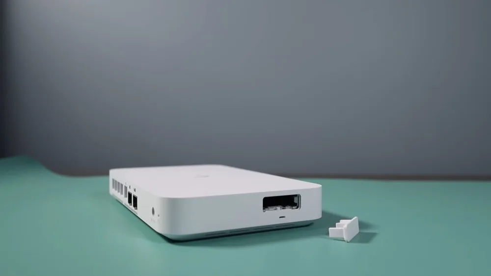 UniFi UCG Fiber с портами, идеальное для сетевой связи, расположено на бирюзовой поверхности рядом с небольшой пластиковой деталью-разъёмом.
