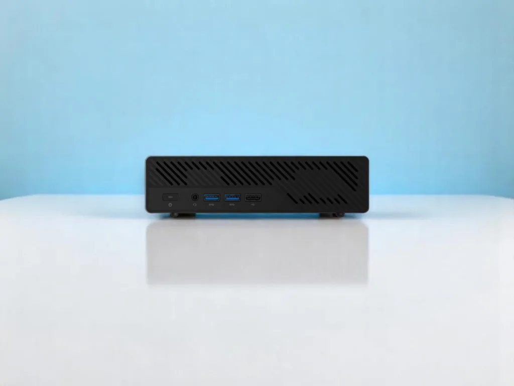 MinisForum MS-A2. Вид спереди компактного черного мини-ПК с USB-портами и кнопкой питания на белой поверхности и голубом фоне