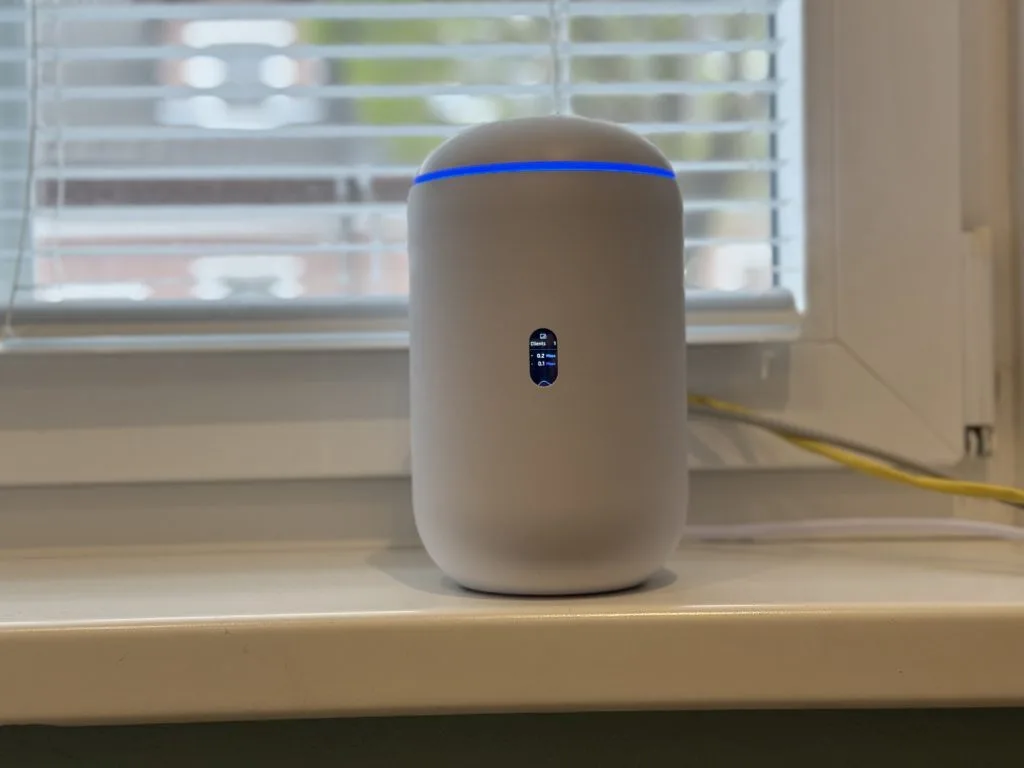 UDR7. Современный белый умный Wi-Fi роутер с LED-индикатором и цифровым экраном на подоконнике