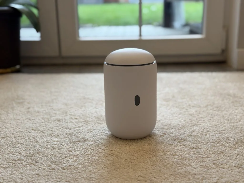 UniFi Dream Router 7. Современный белый очиститель воздуха на бежевом ковре перед стеклянной дверью