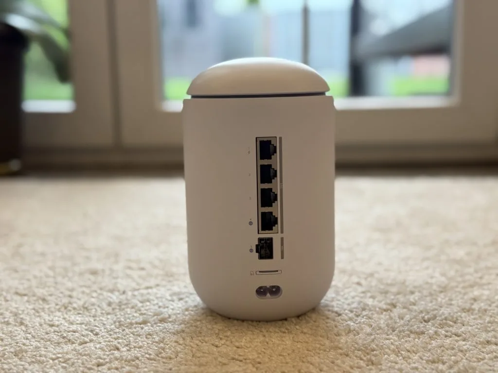 UniFi Dream Router 7. Белый беспроводной маршрутизатор с несколькими Ethernet-портами стоит на бежевом ковре
