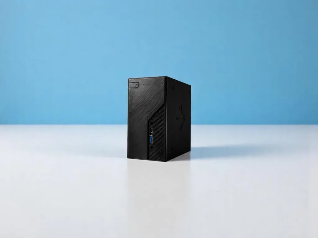 ASRock DeskMini X600. Компактный черный мини-ПК с USB-портами на белой поверхности и голубом фоне